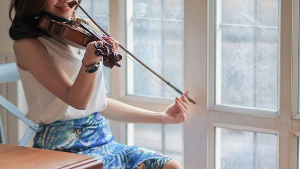 junge Geigerin übt Geige im Musikübungsraum zur Konzertvorbereitung und minimiert Fehler bei Live-Auftritten. Geige ist ein sehr beliebtes und schönes Saiteninstrument. - Foto, Bild