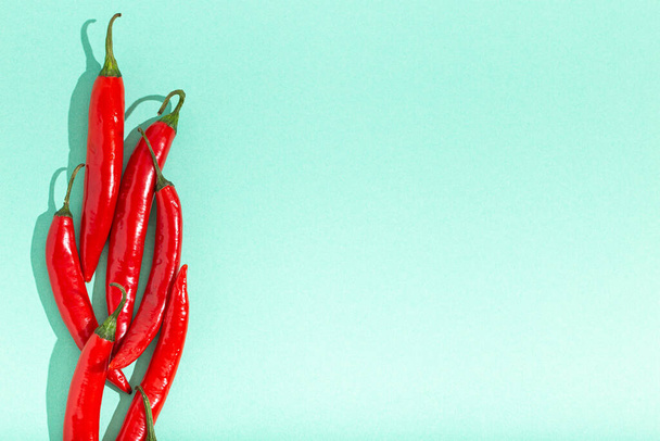 Κόκκινες καυτερές πιπεριές τσίλι σε φόντο ελάχιστης μπλε αντίθεσης - Φωτογραφία, εικόνα
