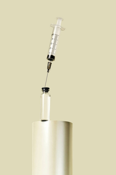Transparent glass jar with disposable syringe on a pastel background. Medical concept of prevention, immunization, vaccination and treatment of coronavirus infection - Foto, afbeelding