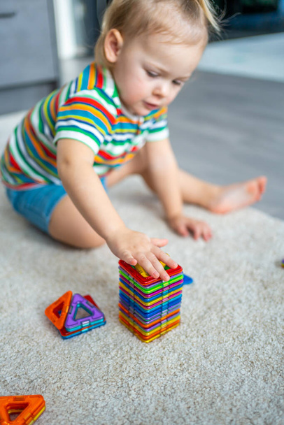 Little girl playing colorful magnet plastic blocks kit at home. The child playing educational games. Early childhood development. - Photo, Image