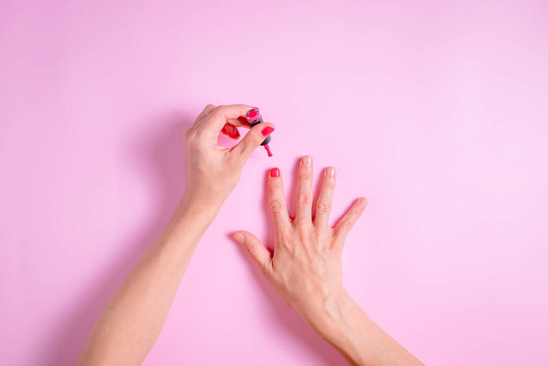 Женские руки при нанесении красного лака для ногтей - Фото, изображение