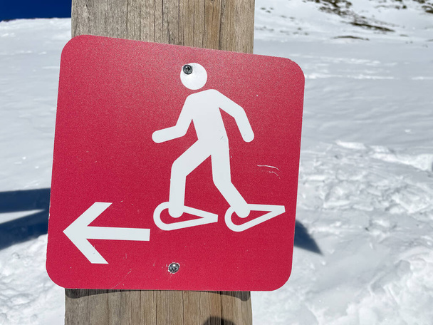 İspanyol Pirenesi 'ndeki Nuria Vadisi dağlarında tahta bir direkte kırmızı kar raketleri sembolü. - Fotoğraf, Görsel