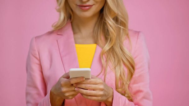 Cropped view of blurred woman using smartphone isolated on pink  - Foto, imagen