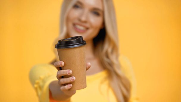 Coffee to go in hand of blurred woman isolated on yellow - 写真・画像