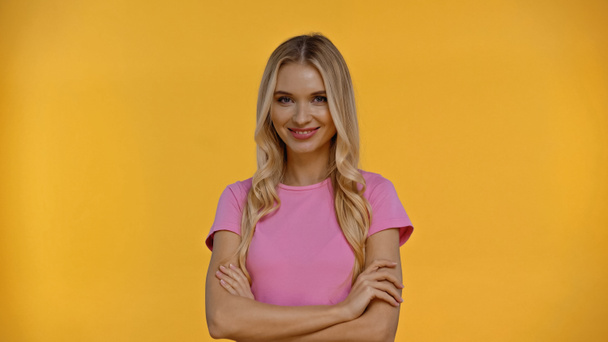 Smiling blonde woman crossing arms and looking at camera isolated on yellow  - Φωτογραφία, εικόνα