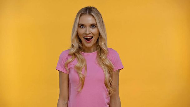 Excited blonde woman in t-shirt looking at camera isolated on yellow  - Zdjęcie, obraz
