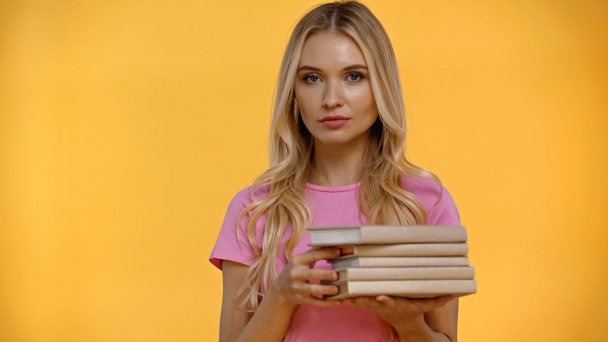 Blonde woman holding blurred books isolated on yellow  - Fotoğraf, Görsel