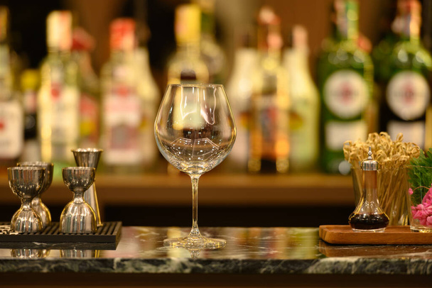 黒大理石のテーブルの上にクリアガラスと背景にアルコールボトルと美しいボケ棚。バーコンセプト. - 写真・画像