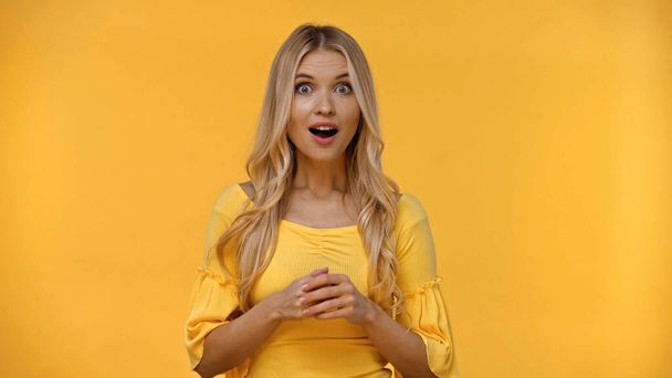 Excited blonde woman in blouse looking at camera isolated on yellow  - Foto, Imagen