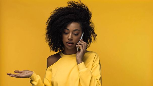 kręcone Afryki amerykanka kobieta mówi przez telefon komórkowy odizolowany na żółty - Zdjęcie, obraz