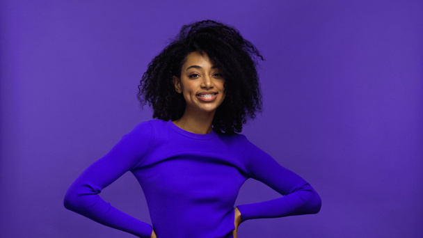 cheerful african american young woman with braces looking at camera isolated on purple  - Foto, Bild