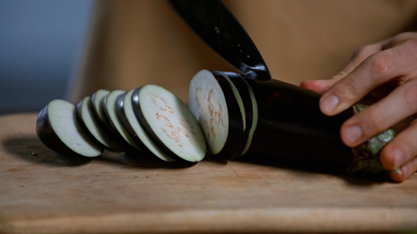 close-up zicht op de mens snijden aubergine op snijplank - Foto, afbeelding
