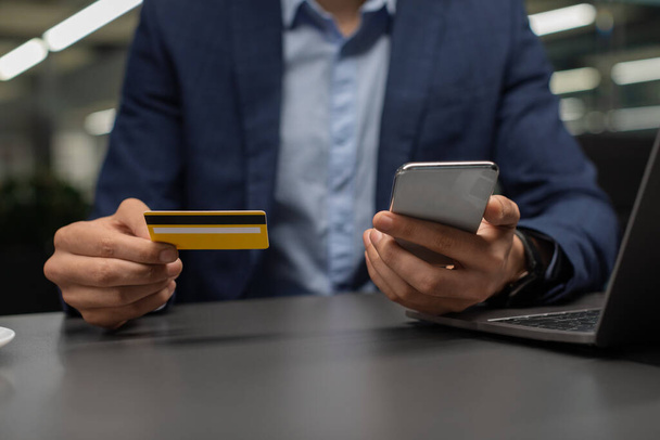 Cropped of entrepreneur using smartphone, holding credit card - Foto, immagini