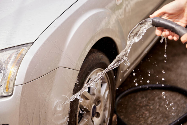 Lavare l'auto con acqua da sotto i tubi. Routine a casa. Prendersi cura del proprio veicolo - Foto, immagini
