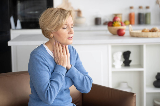Side view of sad middle-aged woman touching neck when feeling unwell with throat. Healthcare and medicine. Health problems concept. Bacterial infections - Photo, Image