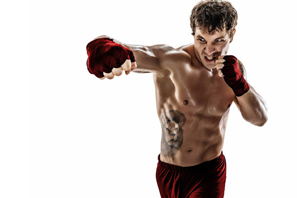Porträt eines aggressiven Boxers, der auf weißem Hintergrund trainiert und schwingt. Rote Sportbekleidung - Foto, Bild
