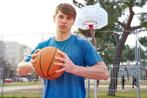 молодий спортсмен тренується на відкритому баскетбольному майданчику. білий чоловік у спортивному одязі грає в баскетбол
. - Фото, зображення