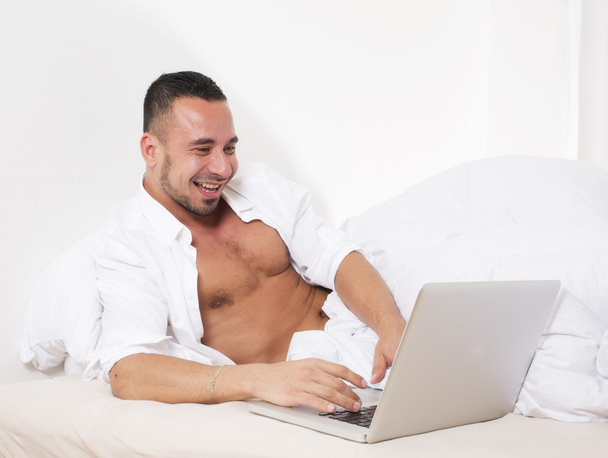 άνθρωπος στο κρεβάτι με το lap-top - Φωτογραφία, εικόνα