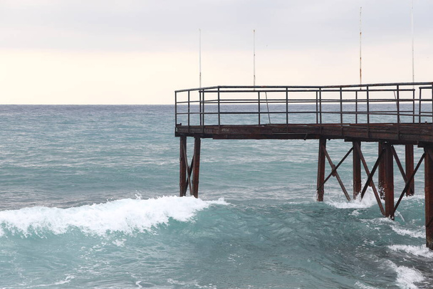 rusty steel beams of the old pier, storm and foamy waves - Foto, Bild