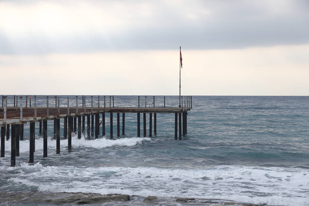 Vihar a tengeren, hab hullámok hátterében a strand móló, Alanya, november 2021 - Fotó, kép