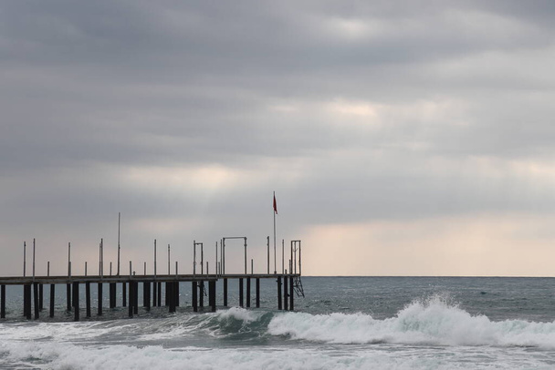 Storm at sea, foam waves against the background of the beach pier, Alanya, November 2021 - Fotoğraf, Görsel