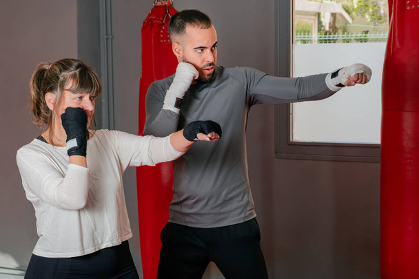 Mature woman at the gym in boxing class with her teacher - Photo, Image