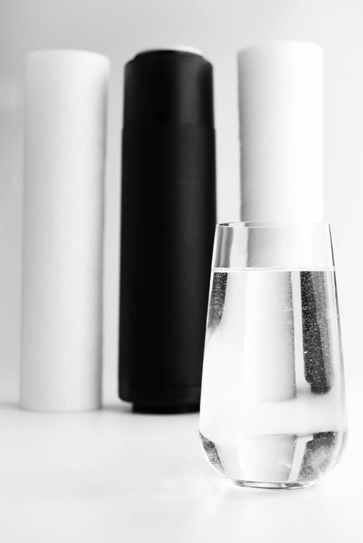 Blurred image of a glass of clean water and water filters in the background.Water filtration concept. - Foto, afbeelding