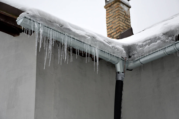 η θερμότητα από το σπίτι περνά μέσα από την οροφή και λιώνει το χιόνι. παγώνει στις σχισμές της οροφής και σχηματίζει παγοκύστες. πρέπει να πραγματοποιείται απώθηση της μόνωσης των δοκών - Φωτογραφία, εικόνα