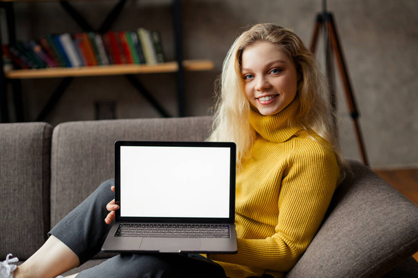 student girl sit on sofa holding laptop looking at mock up screen, online learning on pc, e learning. Closeup view - Photo, Image