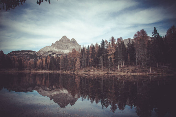 Reflejo de alerces otoñales y picos dolomíticos del lago. Foto efecto Vintage - Foto, imagen