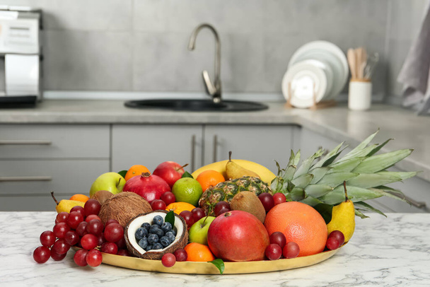 Assortment of fresh exotic fruits on white marble table in kitchen - Photo, Image