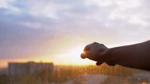 A női kéz eléri a Napot, a Napfényt, megérinti a piszkos ablakot. Közelről. - Felvétel, videó