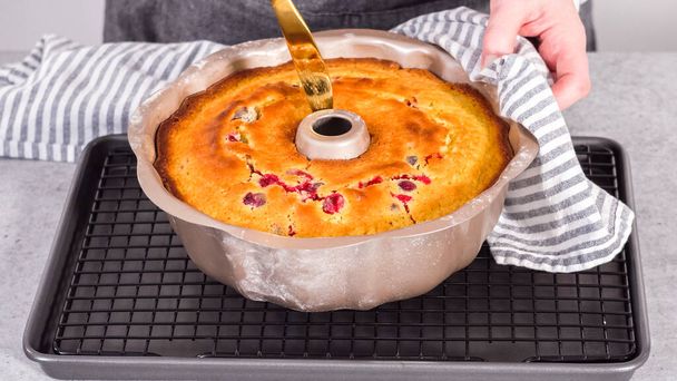Stap voor stap. Koelen citroen cranberry bundt cake op de keuken draad rek. - Foto, afbeelding
