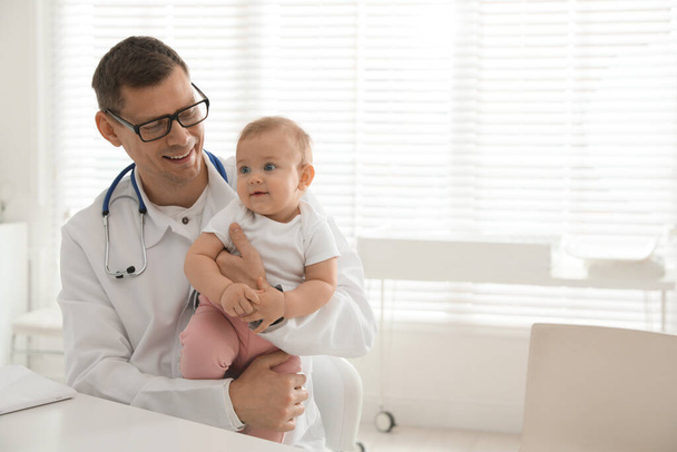 Pediatrician with cute little baby in clinic. Space for text - Foto, Imagen