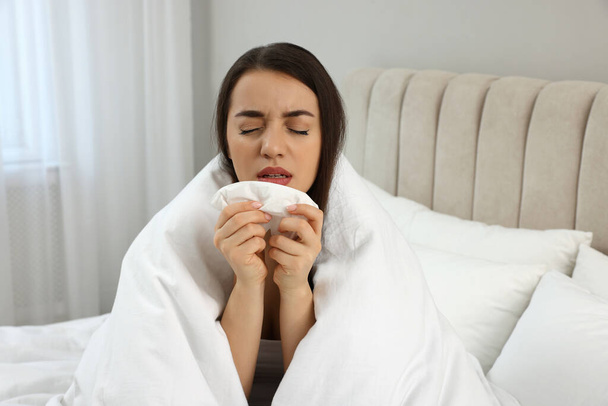 Sick young woman with tissue wrapped in blanket at home - Foto, Imagem