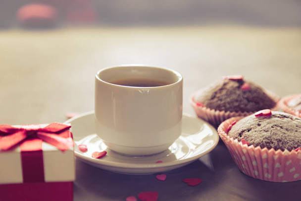 Cup of coffee, chocolate muffins and gift. Sunlight, selective focus, vintage. The concept of a romantic morning, birthday or valentine's day.  - Foto, afbeelding
