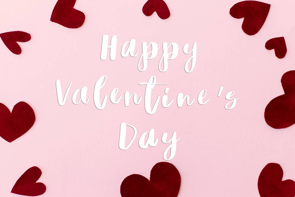 Gelukkige Valentijnsdag tekst op stijlvolle rode harten op roze achtergrond, plat lay. Gelukkige Valentijnsdag wenskaart. Wees mijn Valentijn. Liefde concept - Foto, afbeelding