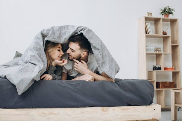 Счастливая пара веселится в постели под одеялом - Фото, изображение
