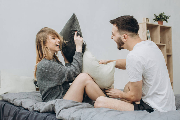Portrait de couple heureux aimant ayant une bataille d'oreillers au lit
 - Photo, image