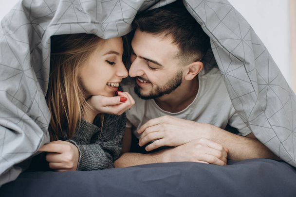 Šťastný pár baví na posteli pod přikrývkou - Fotografie, Obrázek