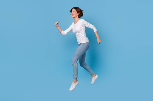 Full size profile side photo of excited cheerful girl traveling on weekend running isolated on blue color background - Фото, изображение