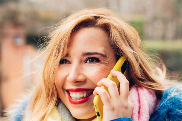 Photo of happy positive fair-haired woman has phone conversation and laughs positively. concept of communication and happiness. - Photo, Image