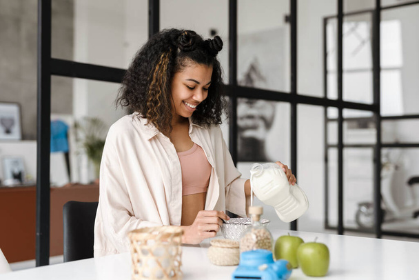 Black young woman smiling while having breakfast at home - Foto, imagen