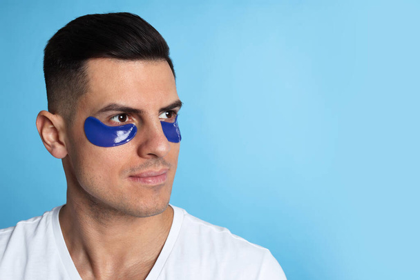 Man with under eye patches on light blue background. Space for text - Fotó, kép