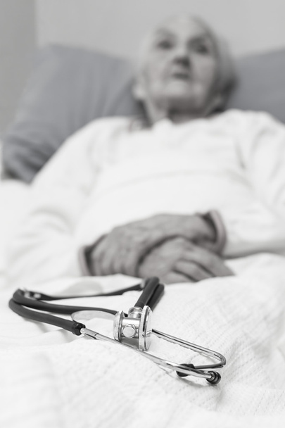 elderly woman lying ill in her bed with a stehoscope  - Foto, Bild