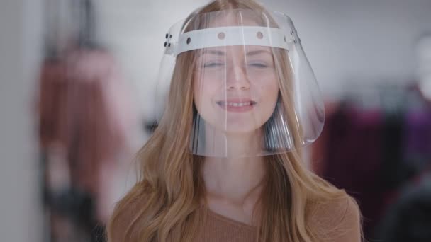 Headshot muotokuva tyttö läpinäkyvä muovi naamio lähikuva nuori valkoihoinen nainen hymyilee katsoen kameran suojaa infektio sepelvaltimovirus henkilökohtaisia suojavarusteita pandemian hallinnan käsite - Materiaali, video