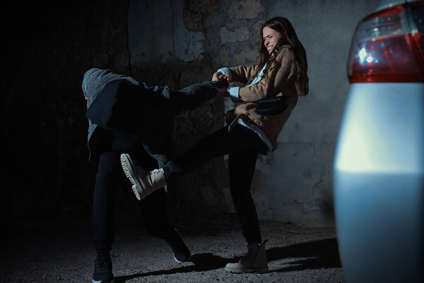 Woman defending herself from attacker on parking lot - 写真・画像