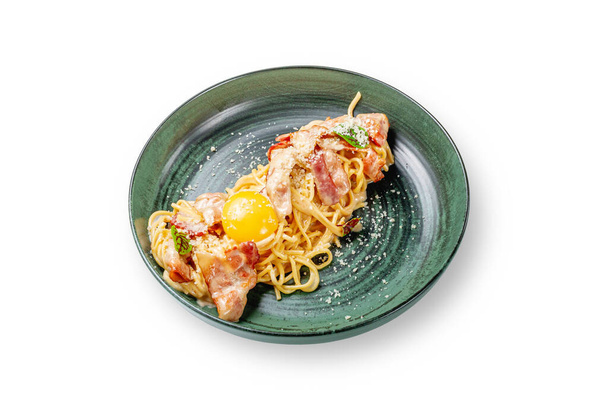 卵の黄身とスパゲッティカルボナーラ.白の隔離された背景にプレート内のパルメザンチーズの下にベーコンとクリームソーススパゲッティのための古典的なレシピ.  - 写真・画像
