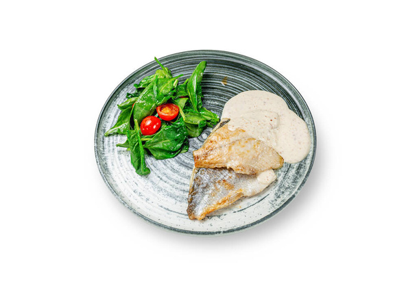 Grillezett hal dorádó pikeperch pürével krém és mártással, spenótsalátával és cseresznye paradicsom egy tányéron fehér izolált alapon  - Fotó, kép