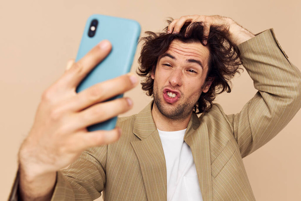 Cheerful man in a suit posing emotions looking at the phone isolated background - Fotó, kép
